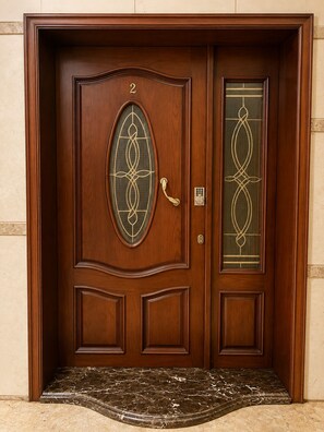 A wooden double door with a number '2' above it, a glass panel with a geometric design, and a small step leading to the entrance. - Spacious 4-bedroom apartment in peaceful New Cairo with AC and gym (New Cairo)