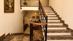 Una maestosa scalinata con gradini in marmo, un lampadario e un quadro incorniciato appeso al muro.