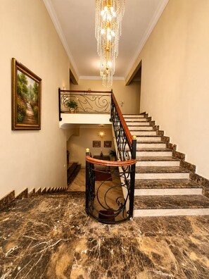 A grand staircase with marble steps, a chandelier, and a framed painting on the wall. - Spacious 4-bedroom apartment in peaceful New Cairo with AC and gym (New Cairo)