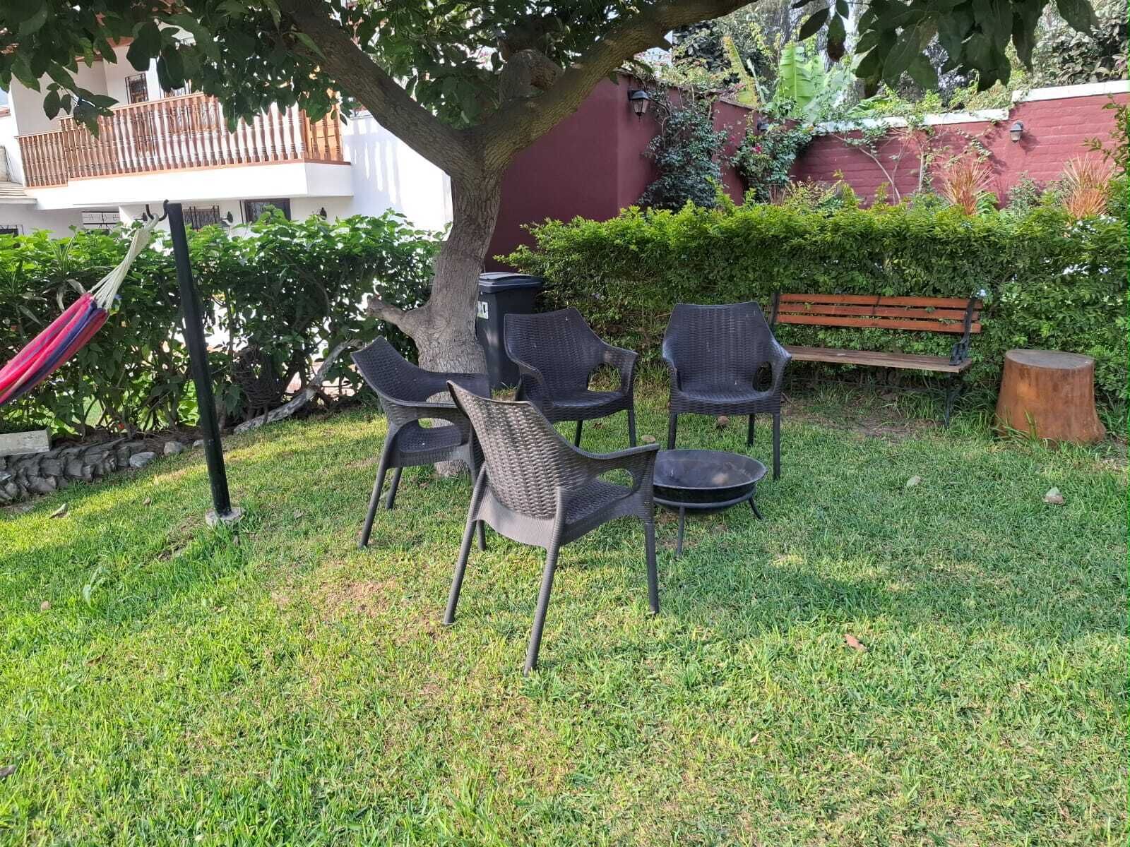 An outdoor seating area with chairs and a table, a hammock, and a tree.