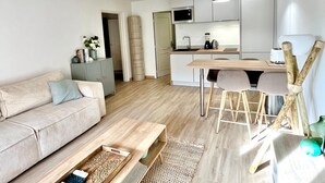 En moderne stue med sofa, sofabord og spiseområde med bord og stole.