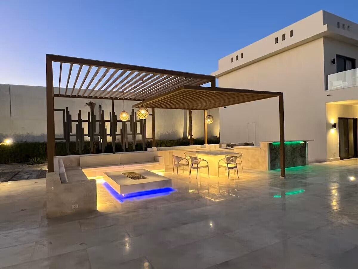 Une terrasse extérieure moderne, dotée d’une pergola, d’un espace salon et d’un comptoir d’accueil.