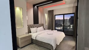 A modern bedroom with a bed, bedside tables, a large window, and a city view.