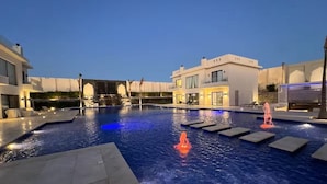 A swimming pool with a water feature, surrounded by buildings.