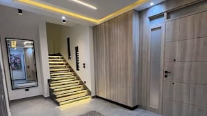 A modern hallway with a staircase, a large mirror, and a wooden wardrobe.