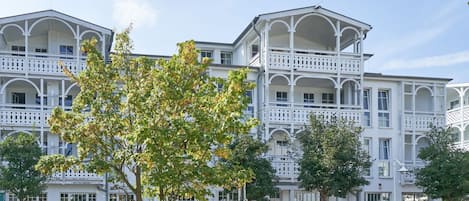 Ein mehrstöckiges Gebäude mit Balkonen, großen Fenstern und einem zentralen Eingang.