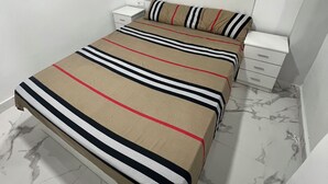 Un dormitorio con cama, mesita de noche, cabecero y piso de mármol.