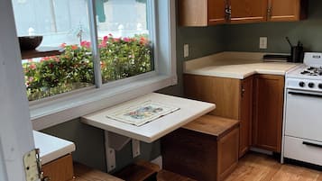 Une cuisine compacte avec des meubles en bois, un plan de travail intégré et une fenêtre donnant sur un jardin.