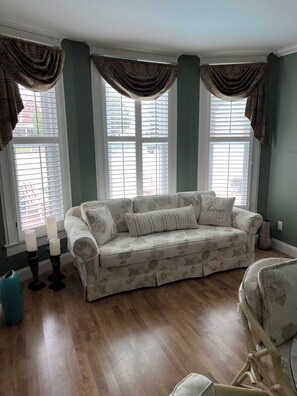 A room with a floral-patterned sofa, a blue vase, and a decorative lamp. - Spacious 3 BR Near I57 > Minutes to Sports Complex, Dining & Spa (Marion)
