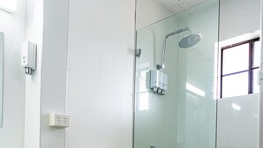 Un bany modern amb dutxa trencadissa de vidre, vàter i un tocador de fusta.