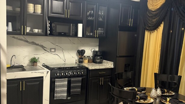A modern kitchen with dark cabinetry, a built-in oven, microwave, and a dining area with a round table and chairs. - La nueva San Migue is a  safe place ,w 2  bedrooms, pool ,restaurants near, (San Miguel)