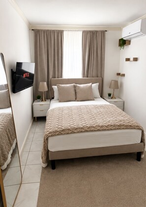 A bedroom with a bed, bedside tables, a TV, and a mirror. - Welcoming 2-bedroom apartment with AC in vibrant Kingston, very central location (Kingston)
