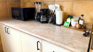 Eine Küche mit Mikrowelle, Kaffeemaschine, Geschirr und Gewürzen.