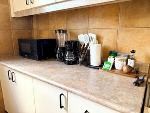 Eine Küche mit Mikrowelle, Kaffeemaschine, Geschirr und Gewürzen.
