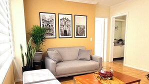 Ein Wohnzimmer mit einer Couch, einem Couchtisch mit einer Vase und einer Zimmerpflanze.
