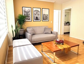 Ein Wohnzimmer mit einer Couch, einem Couchtisch mit einer Vase und einer Zimmerpflanze.