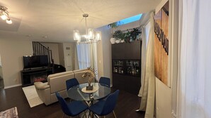 A dining area with a glass table, blue chairs, a chandelier, a fireplace, and a TV in the background. - Luxury 2-Storey Loft in the Heart of Downtown Toronto (Toronto)