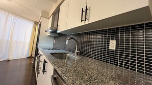 A kitchen with granite countertops, stainless steel sink, black tiled backsplash, and white cabinets. - Luxury 2-Storey Loft in the Heart of Downtown Toronto (Toronto)