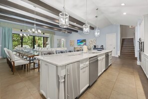 A spacious kitchen with a large island, modern appliances, and a dining area with a view. - Enchanted Estate at Reunion | 9BR Stay w/ Arcades, Theater, and Private pool (Kissimmee)