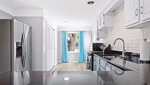 Cozinha moderna com eletrodomésticos de aço inoxidável, bancada preta e armários brancos.