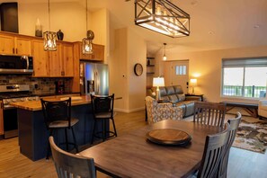 A modern kitchen with wooden cabinets, a central island, and pendant lighting. - Diamond Grove- Pet Friendly- Mountain Chic (Red Lodge)