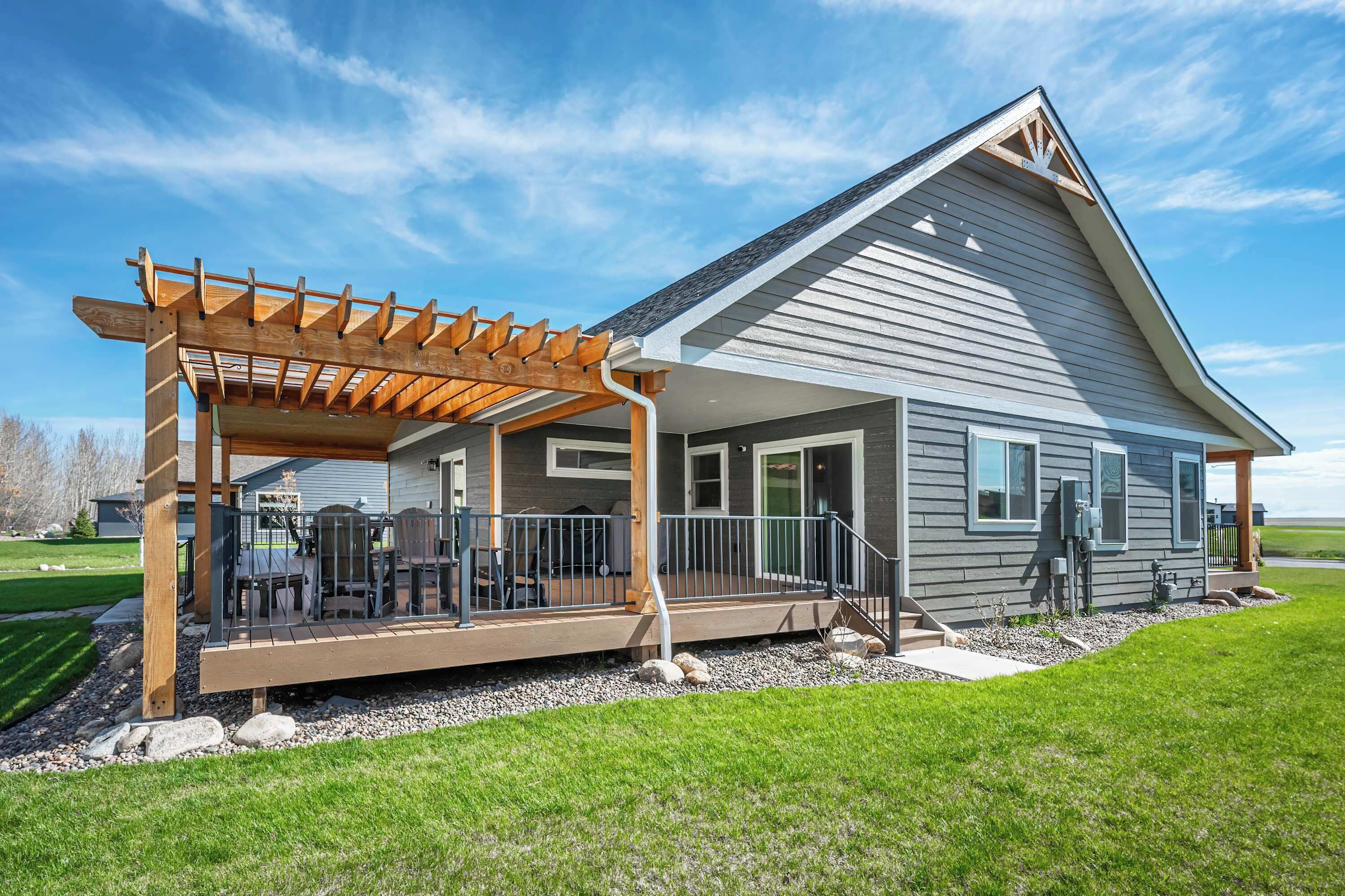 Une maison d’habitation dotée d’un patio couvert, d’une terrasse et d’une pelouse bien entretenue.