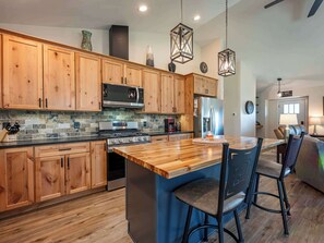 Une cuisine moderne avec des meubles en bois, un îlot central et des tabourets de bar.