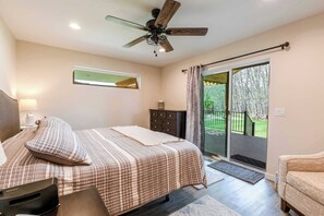 A bedroom with a bed, a ceiling fan, a dresser, a nightstand, and a sliding glass door leading to a balcony. - Diamond Grove- Pet Friendly- Mountain Chic (Red Lodge)