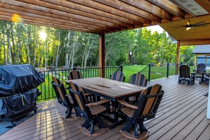 An outdoor deck with a wooden table and chairs, a grill, and a view of a forest. - Diamond Grove- Pet Friendly- Mountain Chic (Red Lodge)