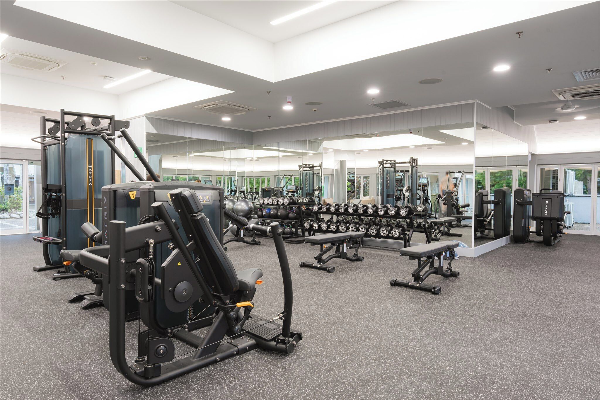 Ein modernes Fitnessstudio mit verschiedenen Trainingsgeräten, darunter Kraftgeräte und Kurzhanteln.