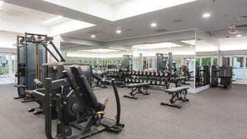 Ein modernes Fitnessstudio mit verschiedenen Trainingsgeräten, darunter Kraftgeräte und Kurzhanteln.
