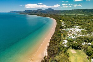 An aerial view of a coastal resort with a sandy beach, dense greenery, and a golf course. - Mirage Resort Villa 150 with access to Sheraton Facilities (Port Douglas)
