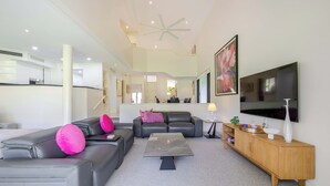 A modern living room with a sectional sofa, a coffee table, and a TV mounted on the wall. - Mirage Resort Villa 150 with access to Sheraton Facilities (Port Douglas)