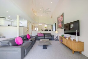 Ein modernes Wohnzimmer mit einer Eckcouch, einem Couchtisch und einem an der Wand befestigten Fernseher.
