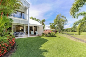 A two-story house with a covered patio, outdoor seating, and a well-maintained lawn. - Mirage Resort Villa 150 with access to Sheraton Facilities (Port Douglas)
