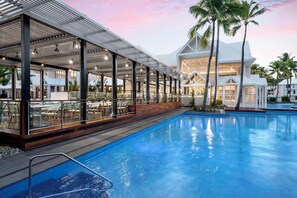 A poolside area with a covered seating area, a pool, and a building with large windows.