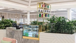A modern lobby with a high ceiling, a reception desk, a glass display case, and a variety of plants. - Mirage Resort Villa 455 with access to Sheraton Facilities (Port Douglas)