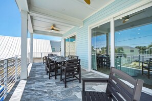 Eine überdachte Terrasse im Freien mit Tisch, Stühlen und einer Bank, mit Blick auf die Umgebung.