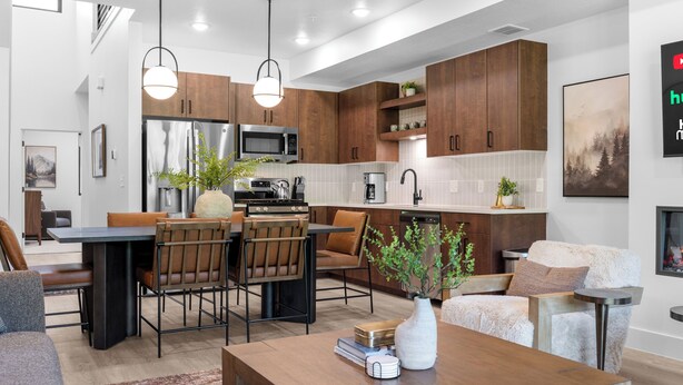 A modern kitchen with wooden cabinets, stainless steel appliances, and a dining area with leather chairs.