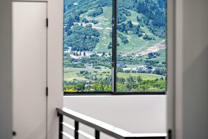 Una habitación con un amplio ventanal que ofrece vistas a un paisaje verde con colinas y árboles.