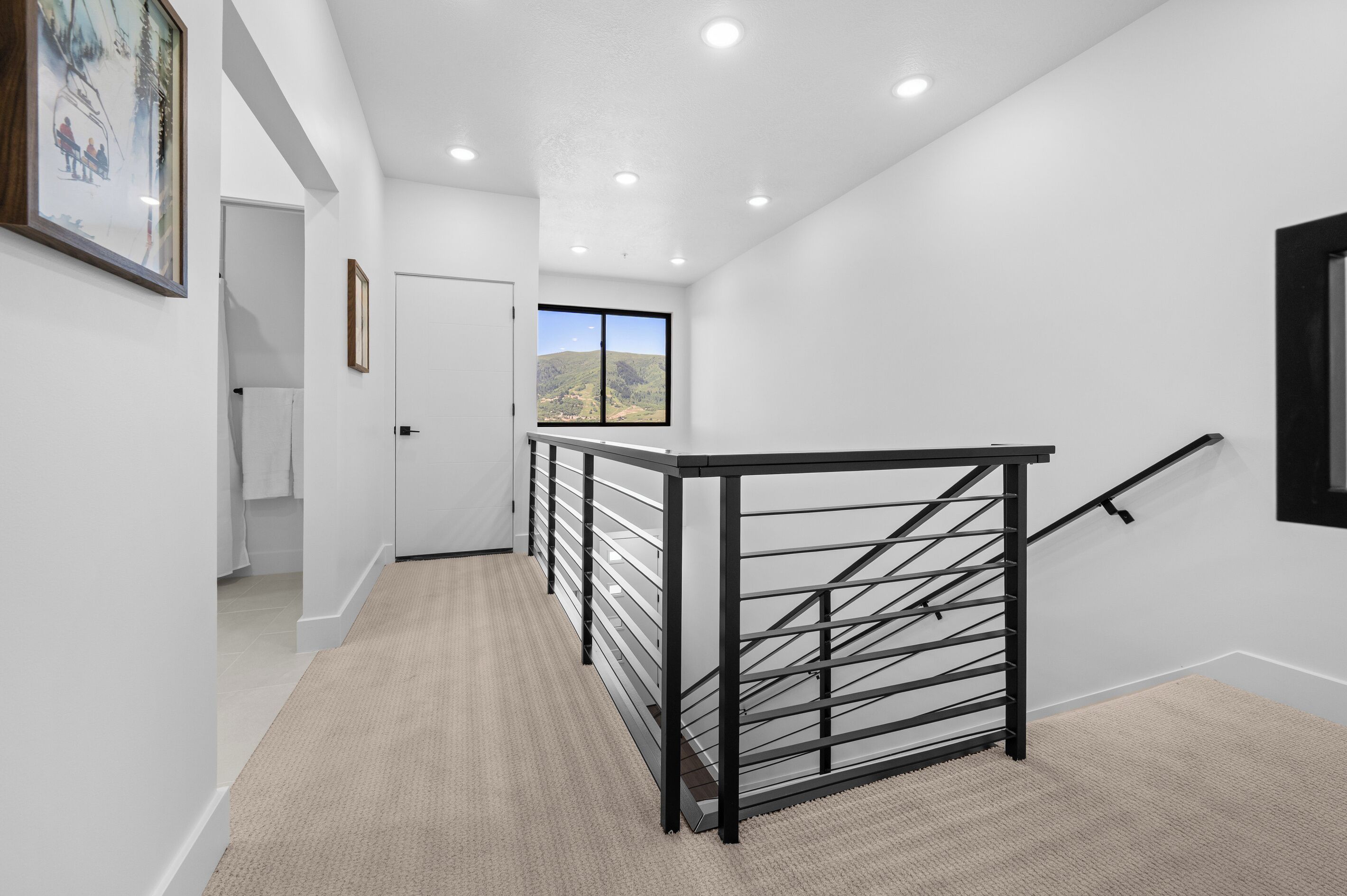 A modern interior with a staircase, white walls, and a view of the outdoors.