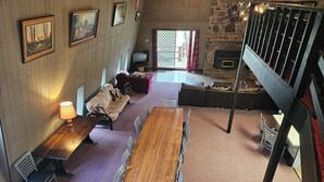 Una habitación amplia con una larga mesa de madera, varias sillas, un sofá y una chimenea de piedra.