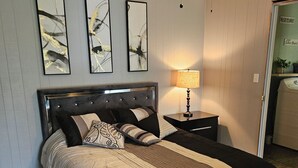 Un dormitorio con cama, mesita de noche, ventilador de techo y decoración en la pared.