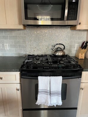 A kitchen with a gas stove, oven, microwave, and a kettle. - Beautiful Ocean Grove Summer & Off-Season Rental (Neptune Township)