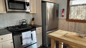 Uma cozinha equipada com fogão, forno, micro-ondas e frigorífico.