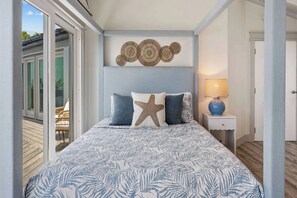 Ein Schlafzimmer mit einem Bett, einem Meerstern-Kissen, einer Wanddekoration und einer Lampe.