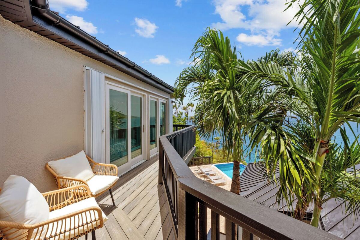 A balcony with wicker chairs and a pool view.