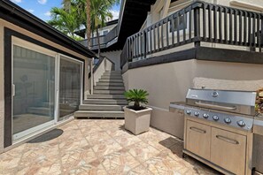 Eine Terrassengruppe mit Grill, einem Blumentopf und einer Treppe zu einem Balkon.
