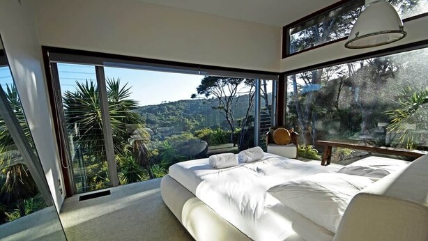 A bedroom with a large bed, a view of a mountainous landscape, and a sliding glass door.