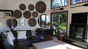 A modern living room with a black leather sofa, a white coffee table, and a fireplace.
